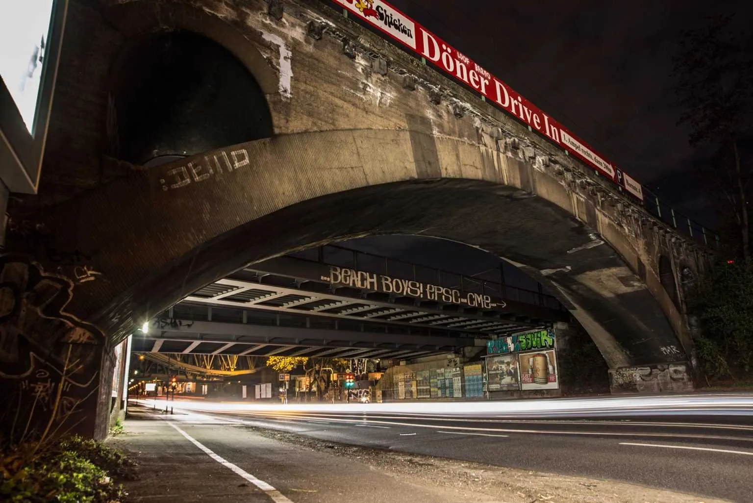 Historic arched bridge at night with long exposure light trails from passing traffic.