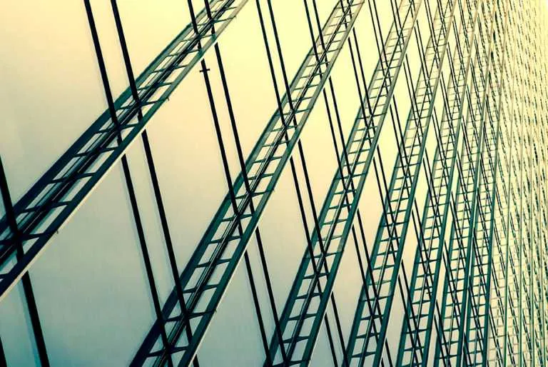 Close-up of a modern glass building facade with repeating metal framework and diagonal lines.