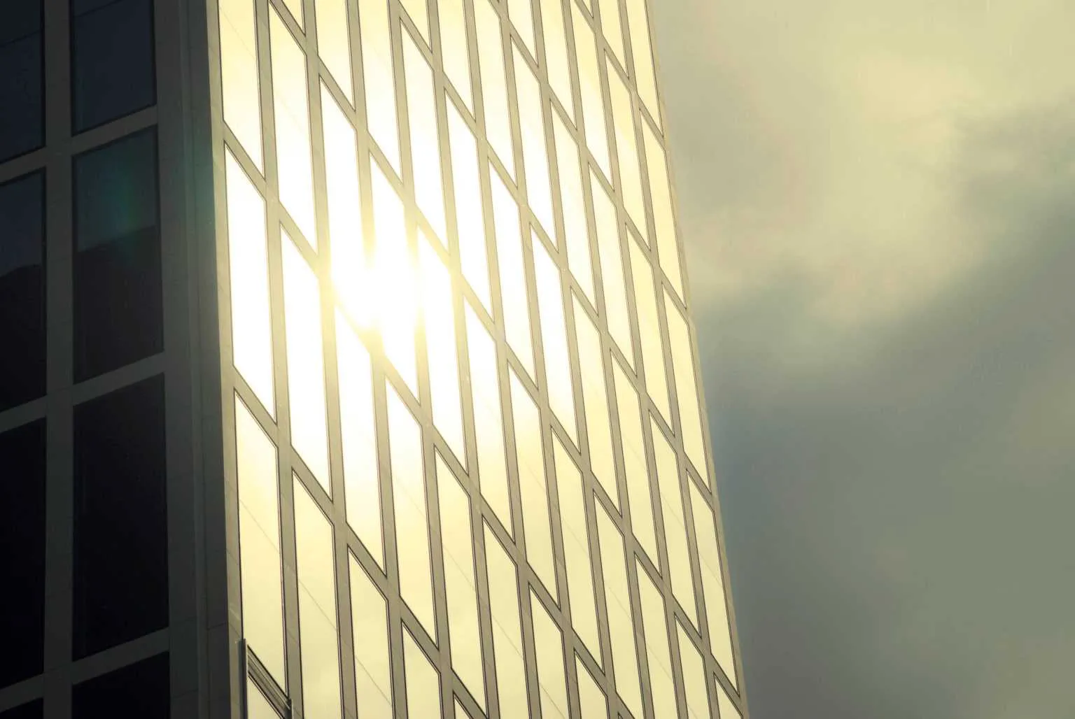 Sunlight reflecting off the glass facade of a modern skyscraper with vertical window lines.